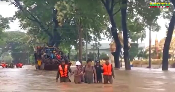 people wade through flood water in Myanmar