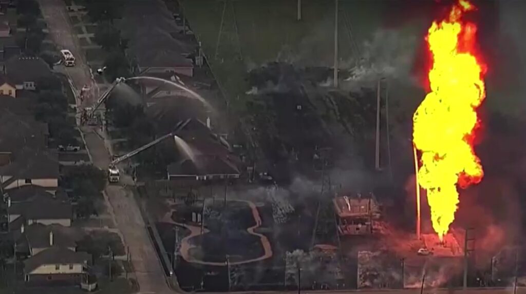 Firetruck spraying water onto houses during massive pipeline fire in La Porte, Texas