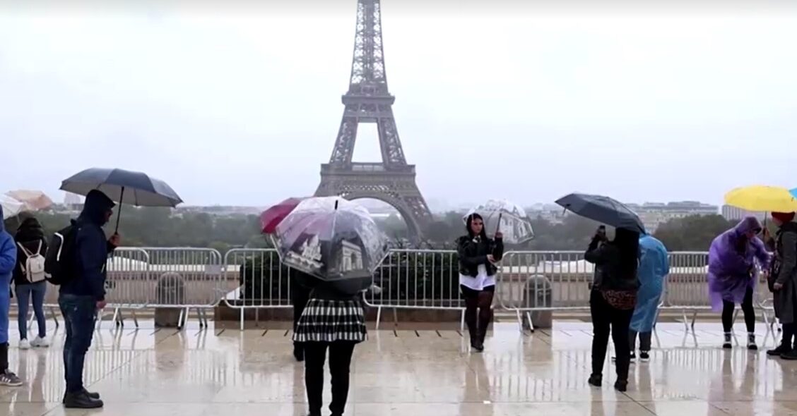 tourists take photo in rain in front of Eiffel