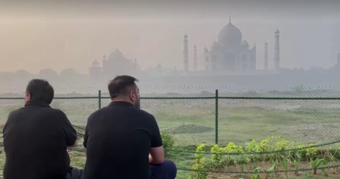 people sitting in front of Taj Mahal amid haze