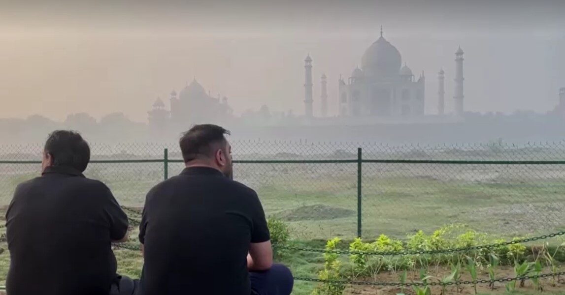 people sitting in front of Taj Mahal amid haze