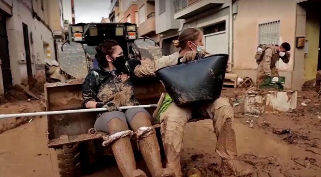 Spain soldier and volunteer clean street covered in mud