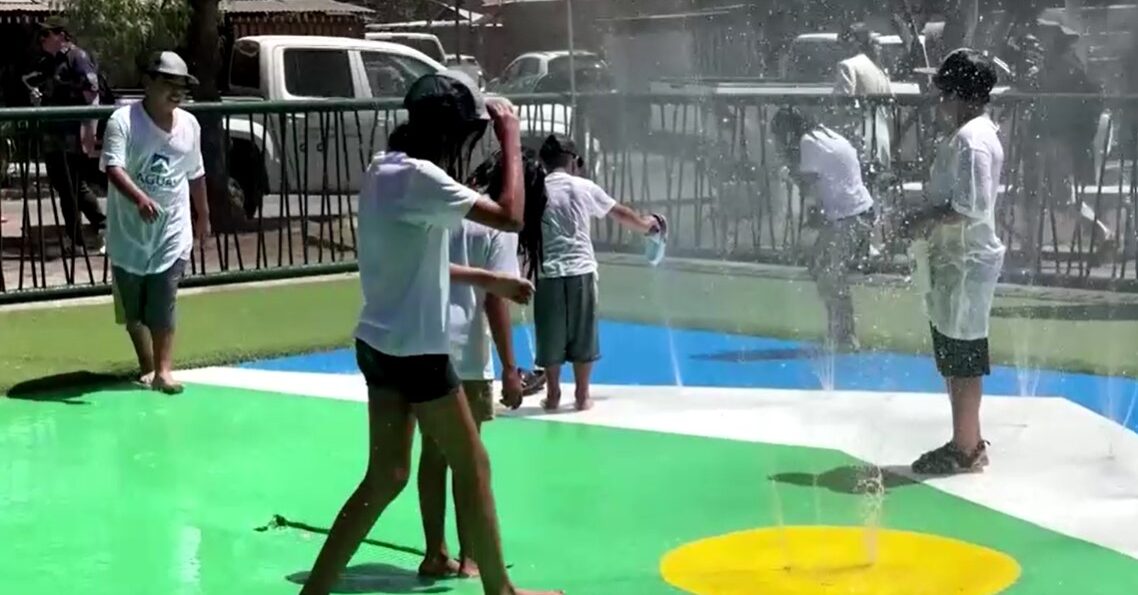 residents in Santiago play with water spring