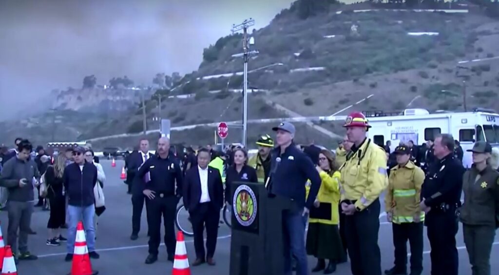 California governor Gavin Newsom warns people against wildfires with huge plumes of smoke seen behind