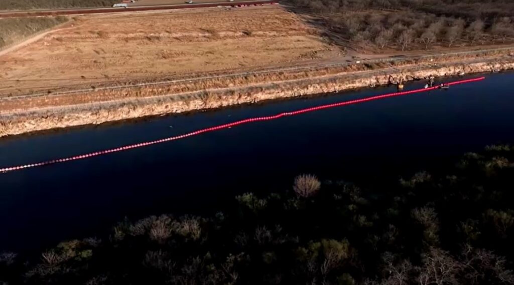 long shot of buoys barrier going up at US-Mexico border river