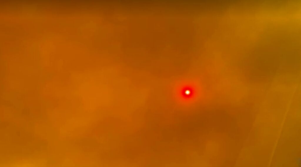 Sun over California covered by wildfire smoke envelopes highway