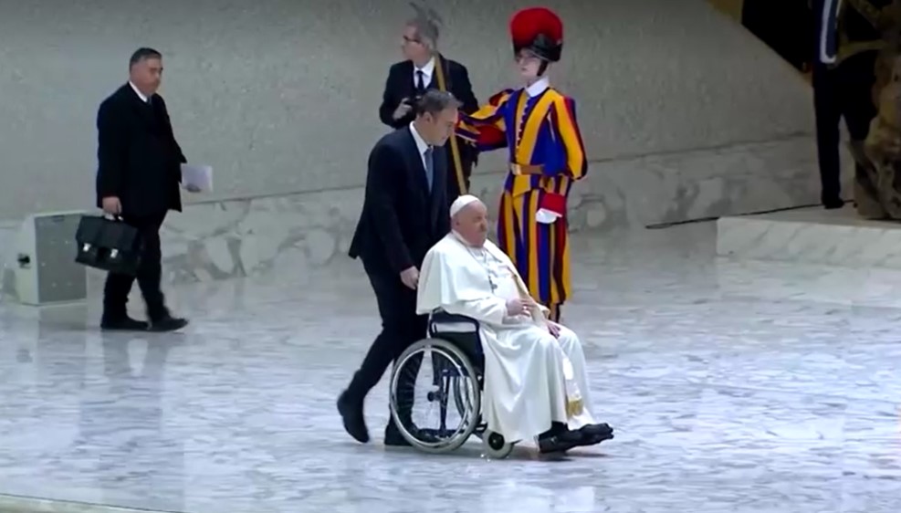 Pope Francis is assisted in a wheelchair as he arrives for the weekly general audience, in Paul VI Audience Hall at the Vatican, February 12, 2025