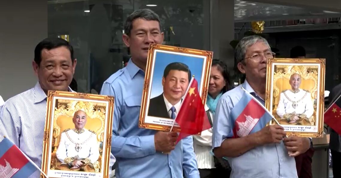 Cambodian people hold portraits of Xi and King Sihamoni