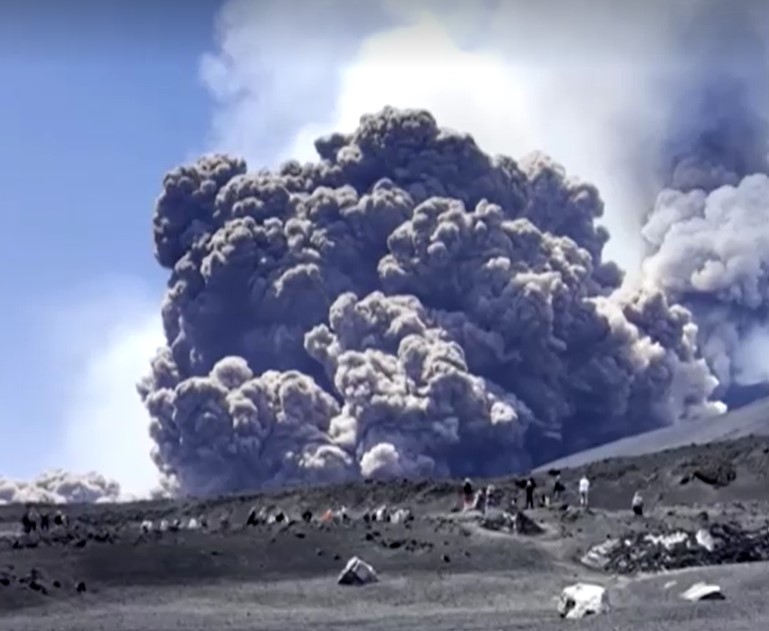 tourists run while Mount Etna erupts