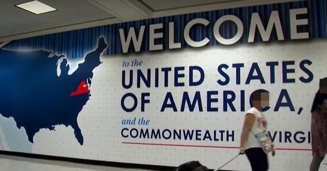 Passengers walk pass welcome sign in Virginia's airport blurred