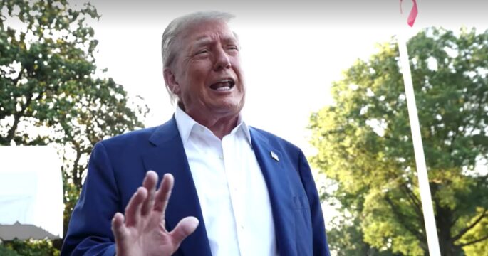 Donald Trump raises hand while talking wirh reporter