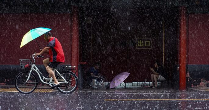 A man riding bicycle while it is raining in Beijing